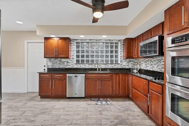 kitchen with tasteful backsplash, appliances with stainless steel finishes, sink, and dark stone counters