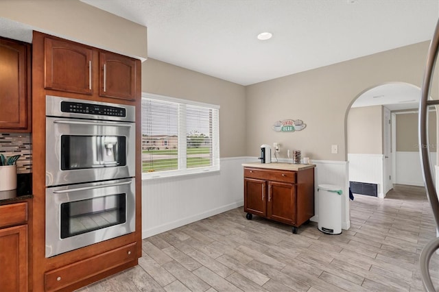 kitchen featuring stainless steel double oven and light hardwood / wood-style floors