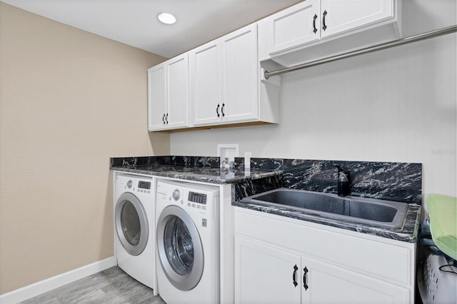 washroom featuring cabinets, sink, washer and dryer, and light wood-type flooring