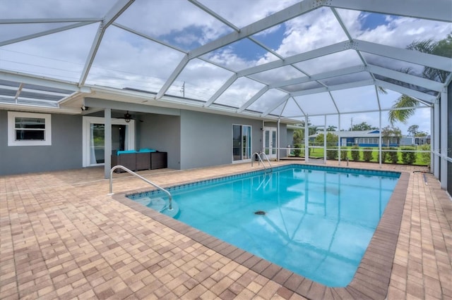 view of swimming pool with an outdoor living space, ceiling fan, glass enclosure, and a patio area