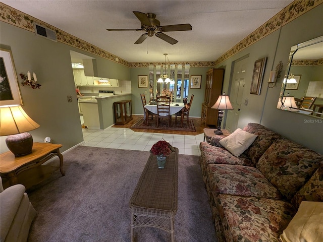 living room featuring ceiling fan with notable chandelier, a textured ceiling, and light tile patterned flooring