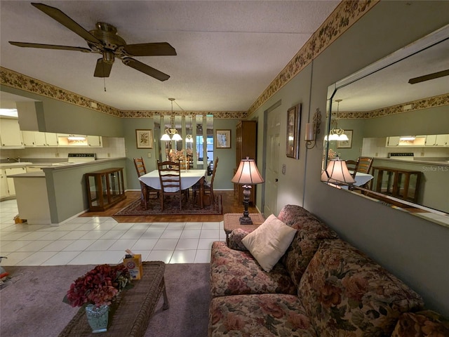 tiled living room featuring ceiling fan with notable chandelier and a textured ceiling