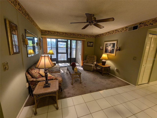 living area with light carpet, ceiling fan, and a textured ceiling