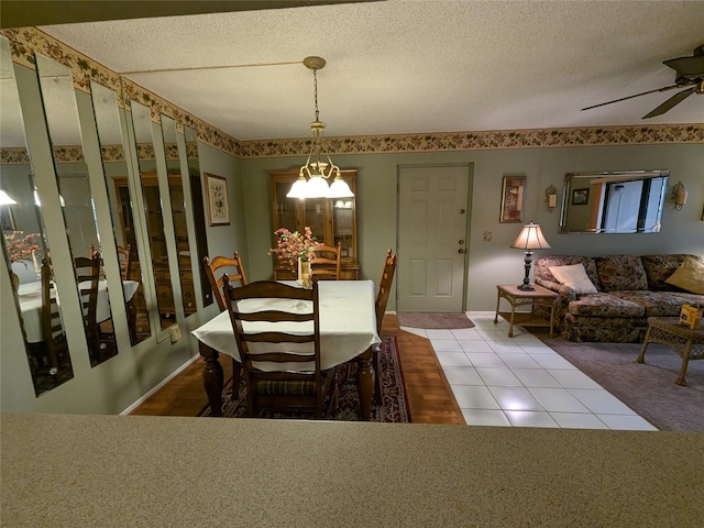 dining area featuring ceiling fan with notable chandelier, tile patterned floors, and a textured ceiling