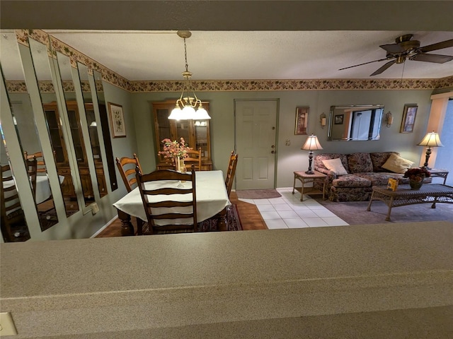 tiled dining space with ceiling fan with notable chandelier and a textured ceiling