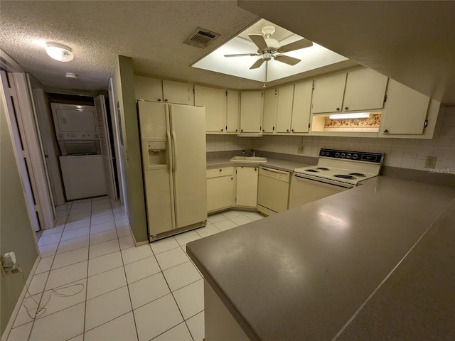 kitchen with sink, backsplash, stacked washer / drying machine, exhaust hood, and white appliances