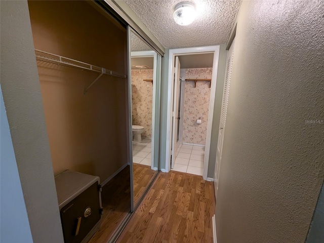 hall with wood-type flooring and a textured ceiling