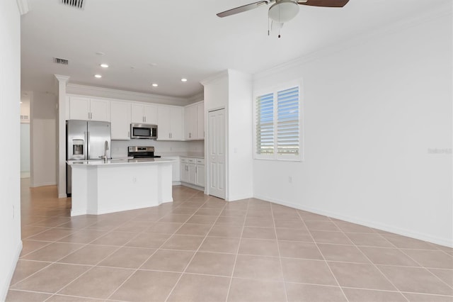 kitchen featuring crown molding, a center island with sink, light tile patterned floors, stainless steel appliances, and white cabinets