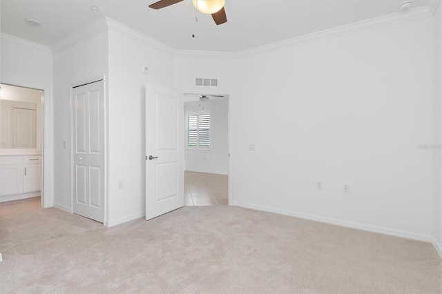 unfurnished bedroom with crown molding, light carpet, ceiling fan, and a closet