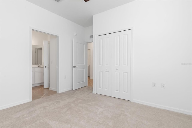 unfurnished bedroom with light carpet, a closet, and ensuite bathroom