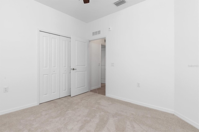 unfurnished bedroom featuring ceiling fan, light carpet, and a closet