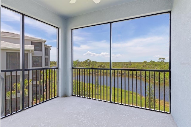 unfurnished sunroom with a water view and ceiling fan