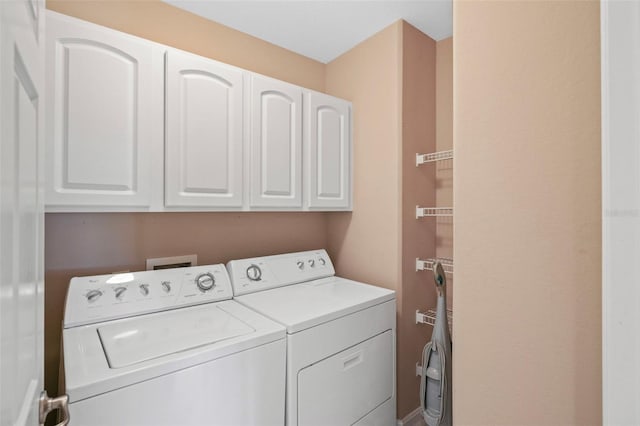 clothes washing area featuring cabinets and washing machine and clothes dryer