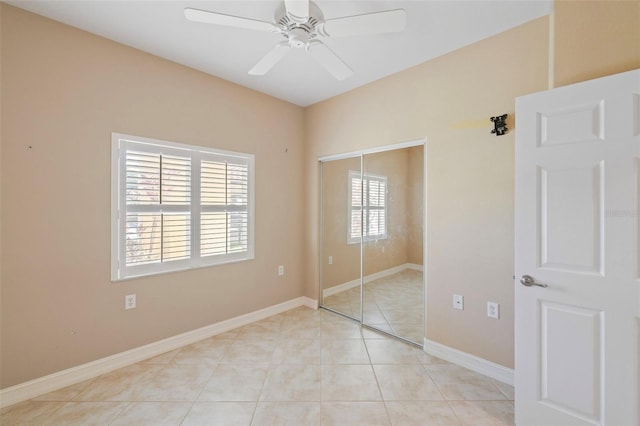 unfurnished bedroom with ceiling fan, a closet, light tile patterned flooring, and multiple windows