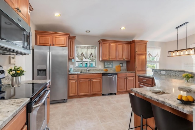 kitchen with decorative light fixtures, sink, appliances with stainless steel finishes, and light stone countertops