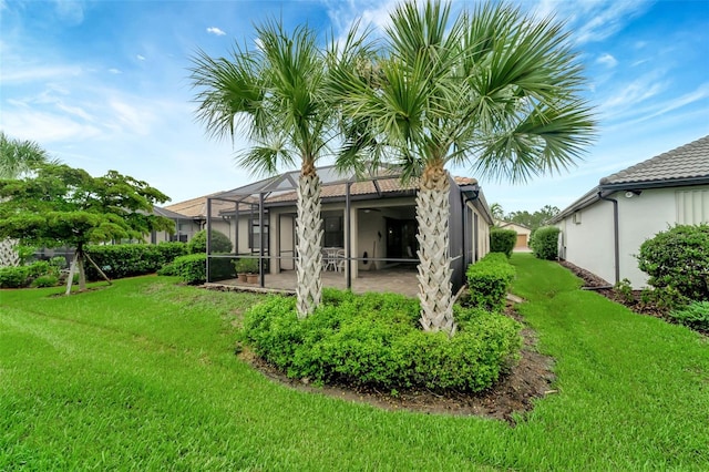 back of house featuring a lawn, glass enclosure, and a patio area