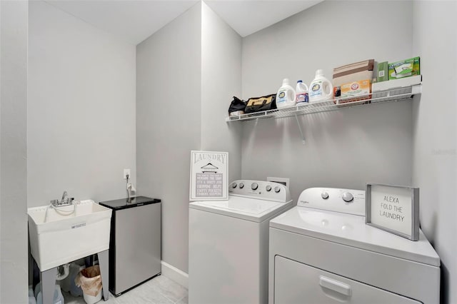 clothes washing area featuring washing machine and dryer, sink, and light tile patterned floors