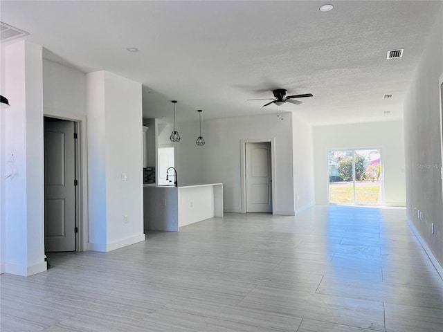 unfurnished living room with sink and ceiling fan