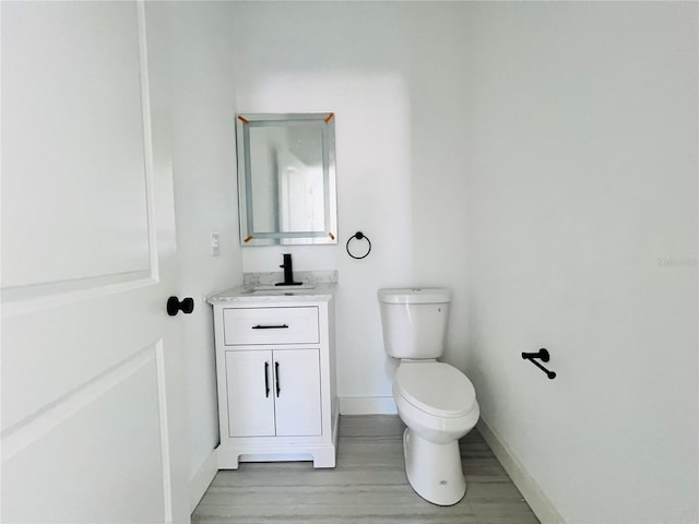 bathroom featuring toilet, wood-type flooring, and vanity