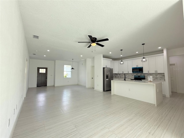 26345 Trinilas Dr, Punta Gorda, FL 33983 - kitchen with light countertops, a kitchen island with sink, stainless steel appliances, open floor plan, and backsplash