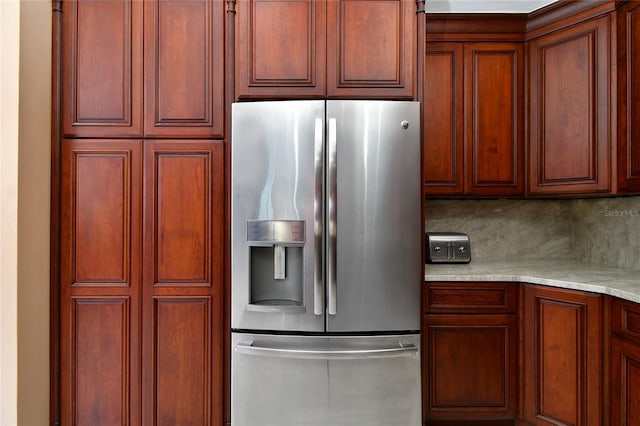 kitchen featuring stainless steel refrigerator with ice dispenser, light stone countertops, and decorative backsplash