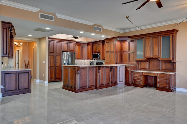 kitchen featuring crown molding, ceiling fan with notable chandelier, built in desk, and appliances with stainless steel finishes