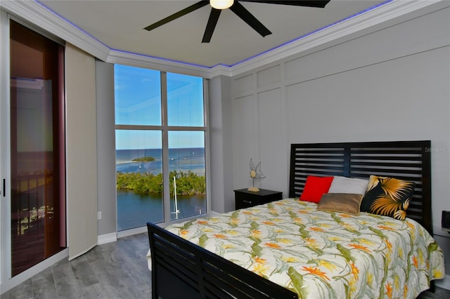 bedroom featuring hardwood / wood-style floors, ornamental molding, access to exterior, ceiling fan, and a water view