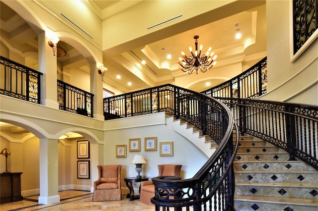 stairway featuring an inviting chandelier, a towering ceiling, and ornamental molding