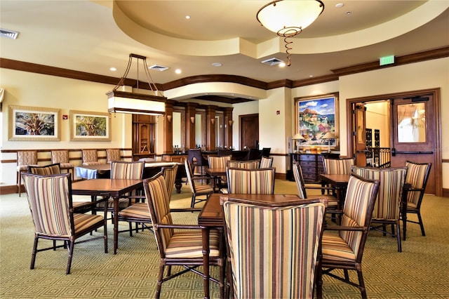 dining space with ornamental molding, a raised ceiling, and carpet