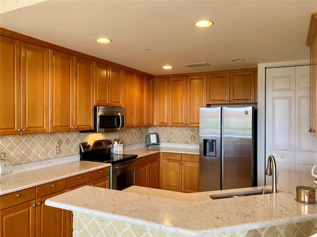 kitchen with appliances with stainless steel finishes, backsplash, light stone counters, and sink