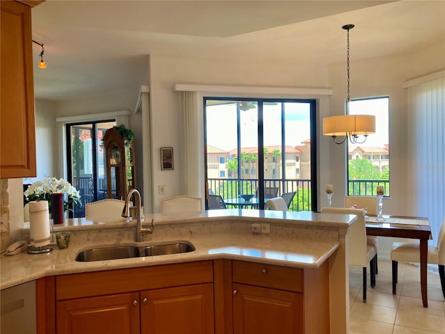 kitchen featuring kitchen peninsula, light tile patterned flooring, dishwasher, hanging light fixtures, and sink