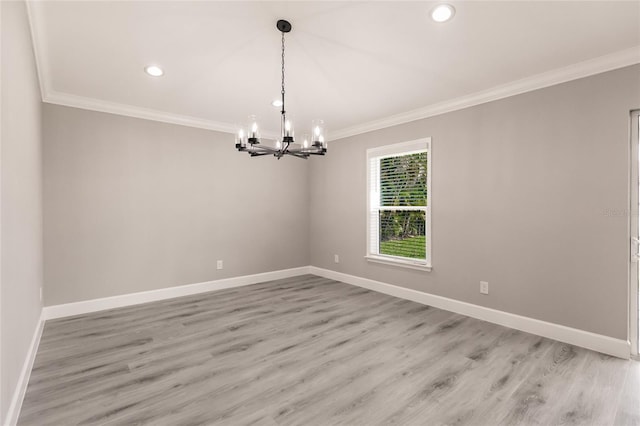 spare room with light hardwood / wood-style floors, ornamental molding, and a chandelier