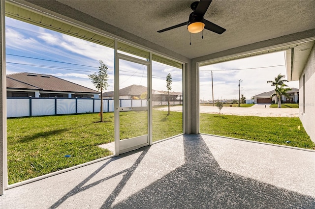 unfurnished sunroom featuring ceiling fan and a wealth of natural light