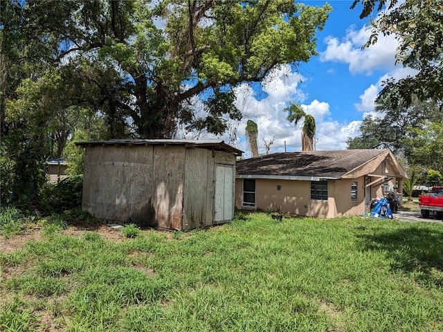 rear view of property with an outbuilding, a shed, stucco siding, and a lawn
