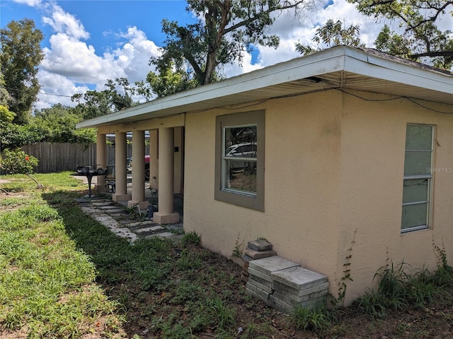view of property exterior featuring stucco siding, fence, and a yard