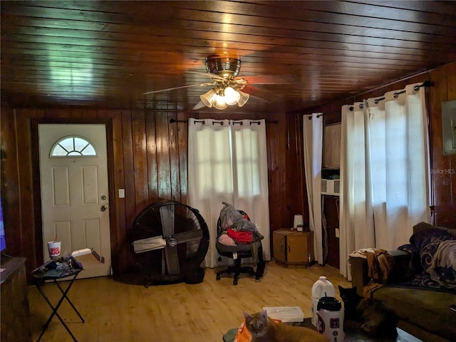 living room featuring wooden ceiling, wooden walls, wood finished floors, and ceiling fan
