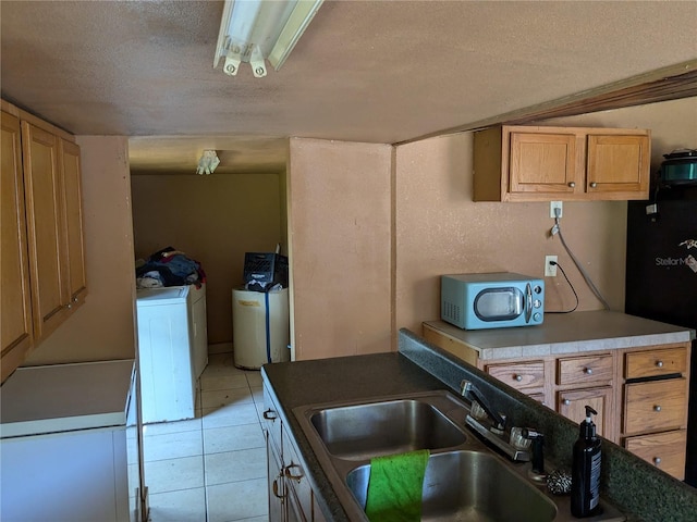 kitchen featuring a sink, a textured ceiling, freestanding refrigerator, independent washer and dryer, and light tile patterned floors