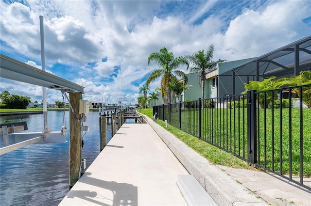 view of dock with a yard, a water view, and a lanai