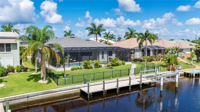 back of property with a yard, a water view, and glass enclosure