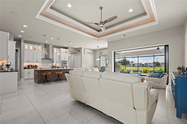 living room with a raised ceiling and ceiling fan