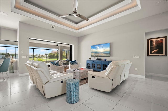 living room with a tray ceiling and ceiling fan