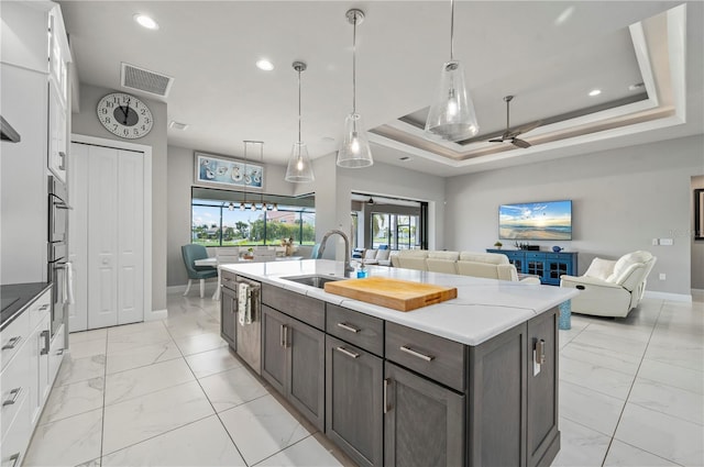 kitchen with dark brown cabinetry, a raised ceiling, ceiling fan, sink, and white cabinetry