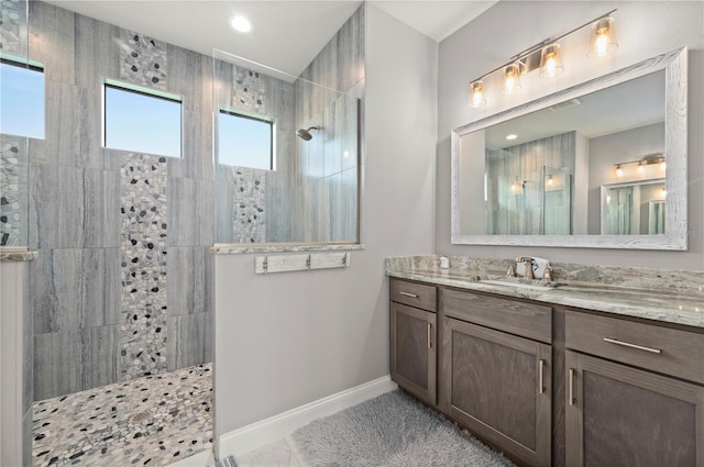 bathroom with a tile shower and vanity