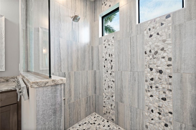 bathroom with tiled shower and vanity