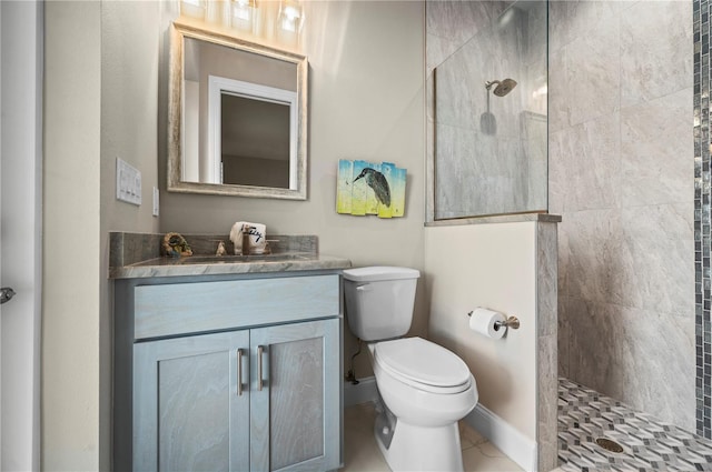 bathroom with tile patterned flooring, vanity, toilet, and tiled shower