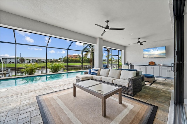 exterior space featuring glass enclosure, a patio area, outdoor lounge area, and a water view