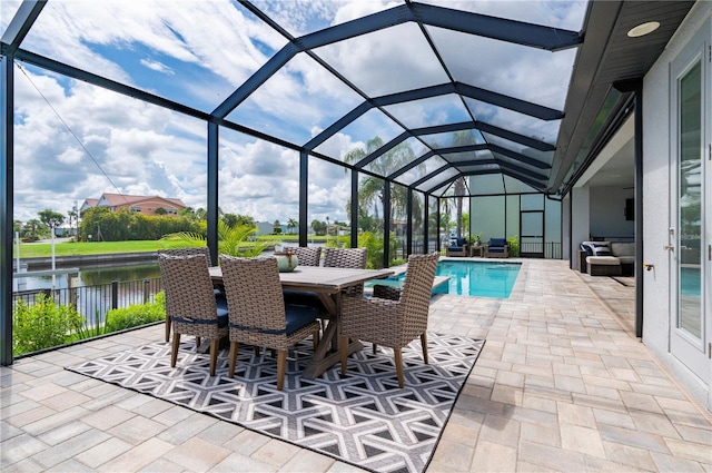 view of pool featuring glass enclosure, a patio area, and a water view