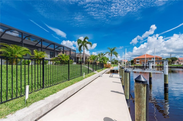 view of dock featuring a lawn, glass enclosure, and a water view