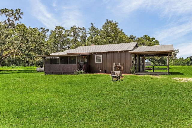 back of property with a lawn and a sunroom