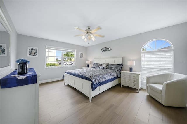 bedroom with multiple windows, ceiling fan, and light hardwood / wood-style flooring